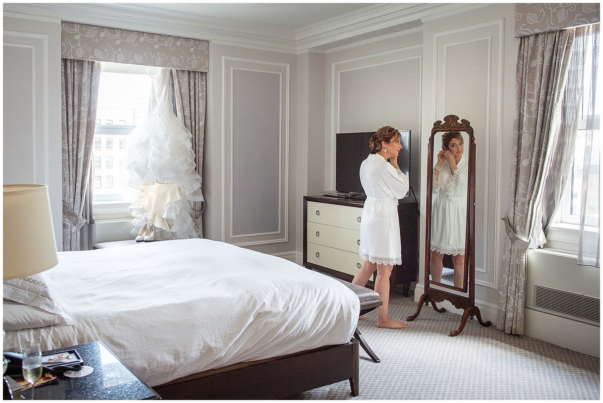 a bride admiring her wedding dress in the window of the Prime Minister suite on her Chateau Laurier wedding day