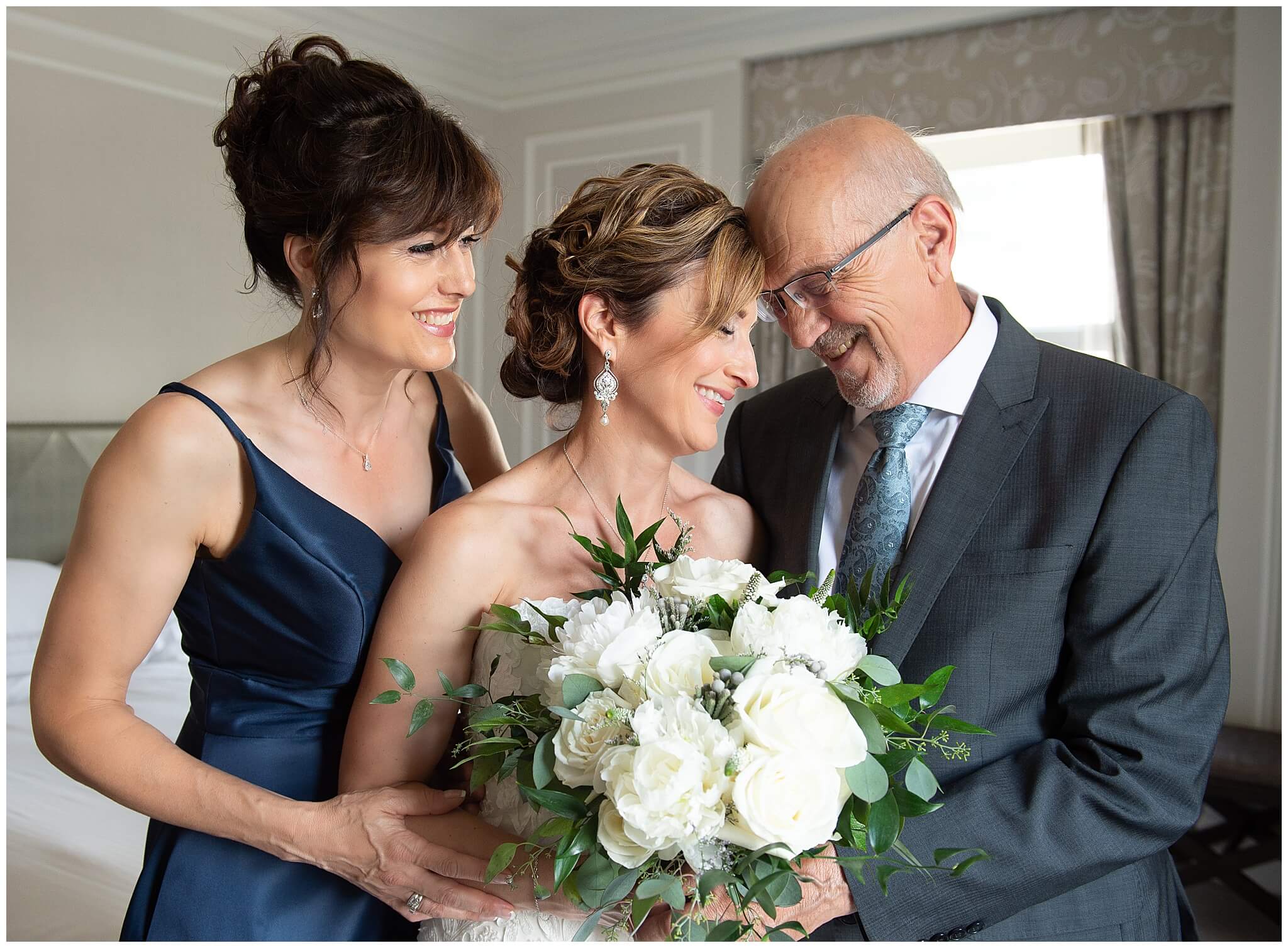 a bride having an intimate moment with her dad and sister before her Chateau Laurier wedding ceremony begins