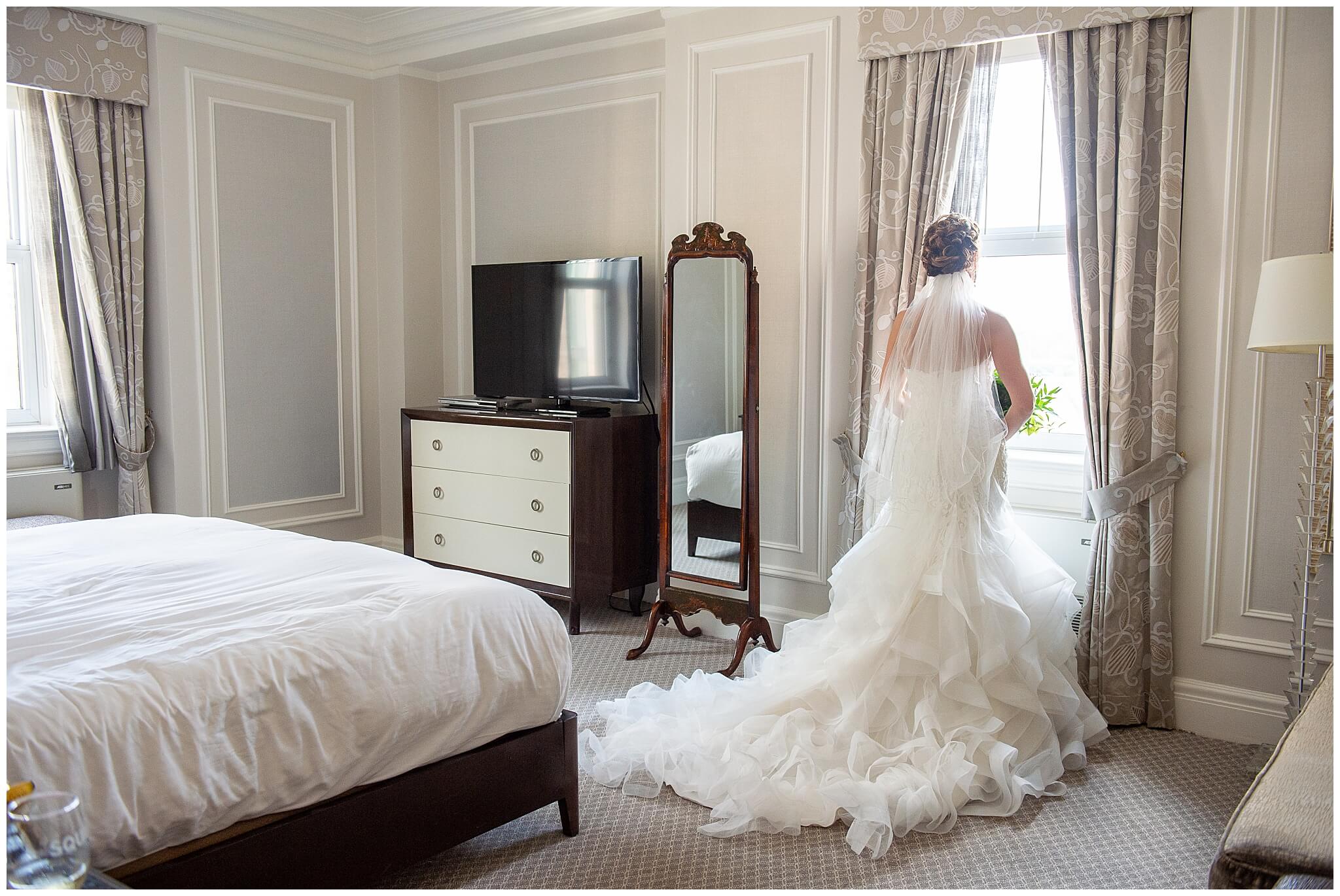 a bride looking out the window in the Prime Minister's Suite as she gets ready for her Chateau Laurier wedding