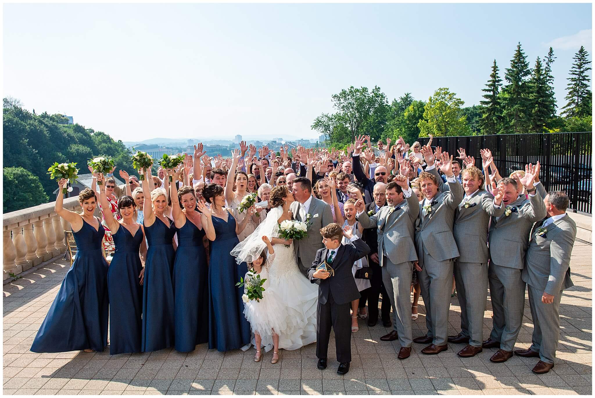 a large group photo of a bride and groom with all their guests cheering on the terrace of the Chateau Laurier hotel