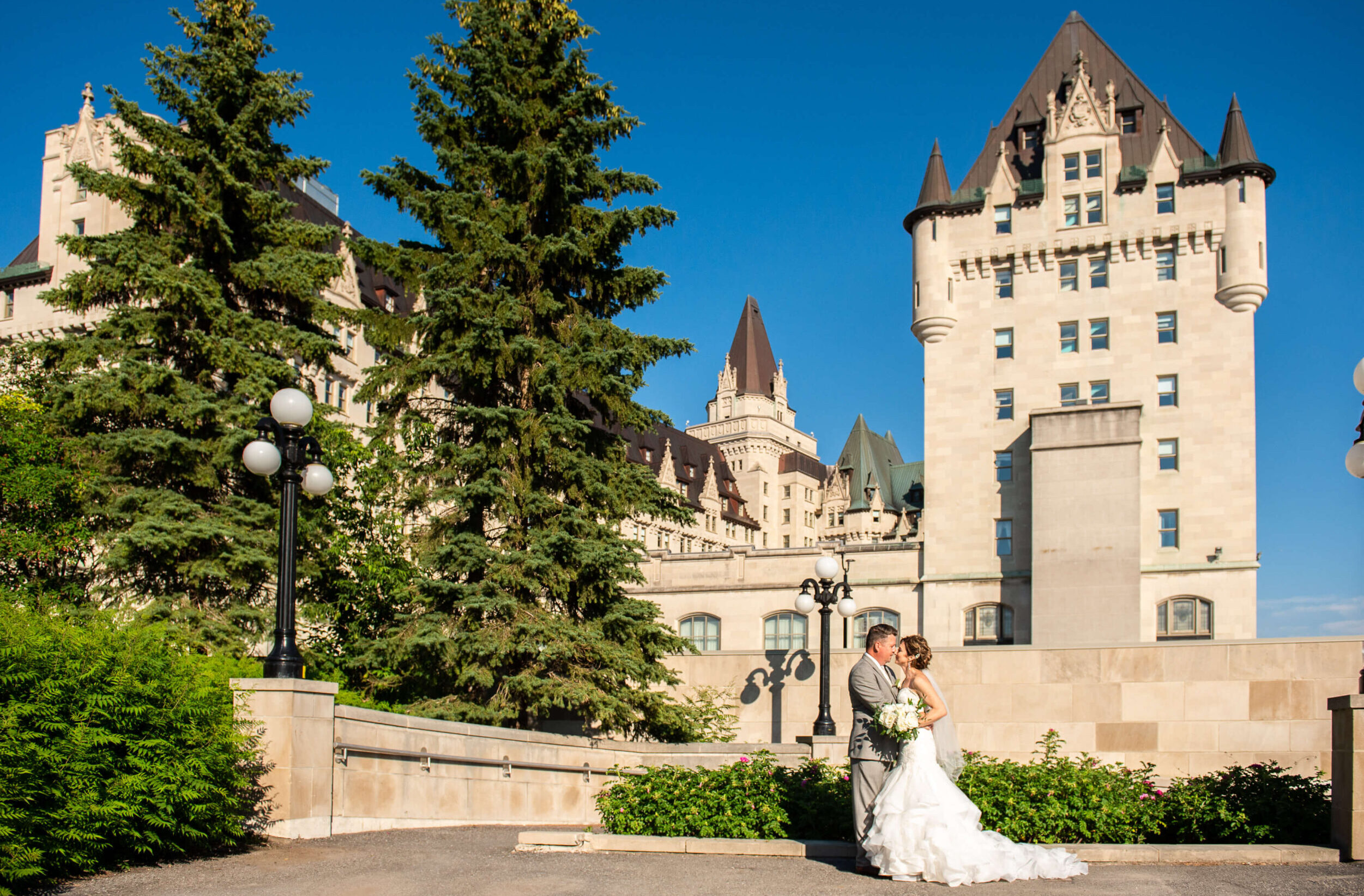 a bride and groom hugging with the scene of the Chateau Laurier weddings venue in the background
