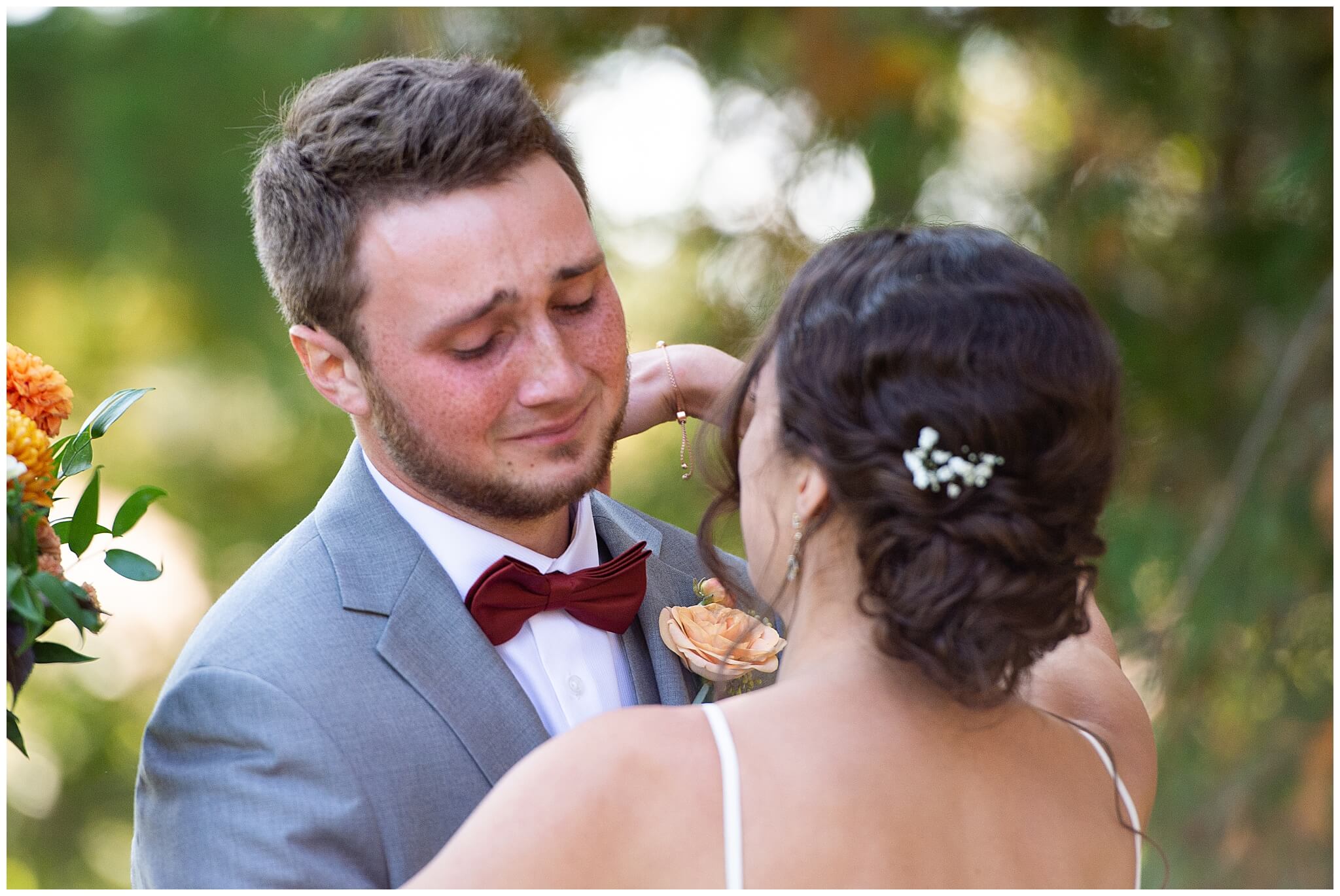 a groom in a grey suit crying emotionally when he sees his bride for the first time during first looks