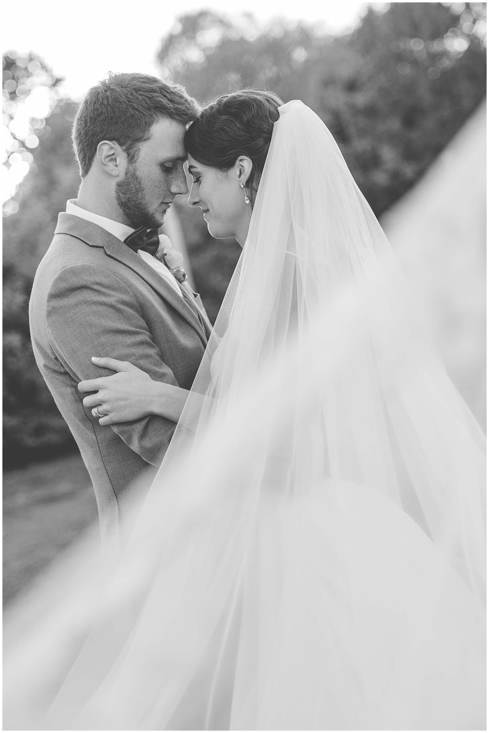 a black and white photo of a bride and groom underneath a veil. Taken outdoors at Strathmere Wedding venue near Ottawa