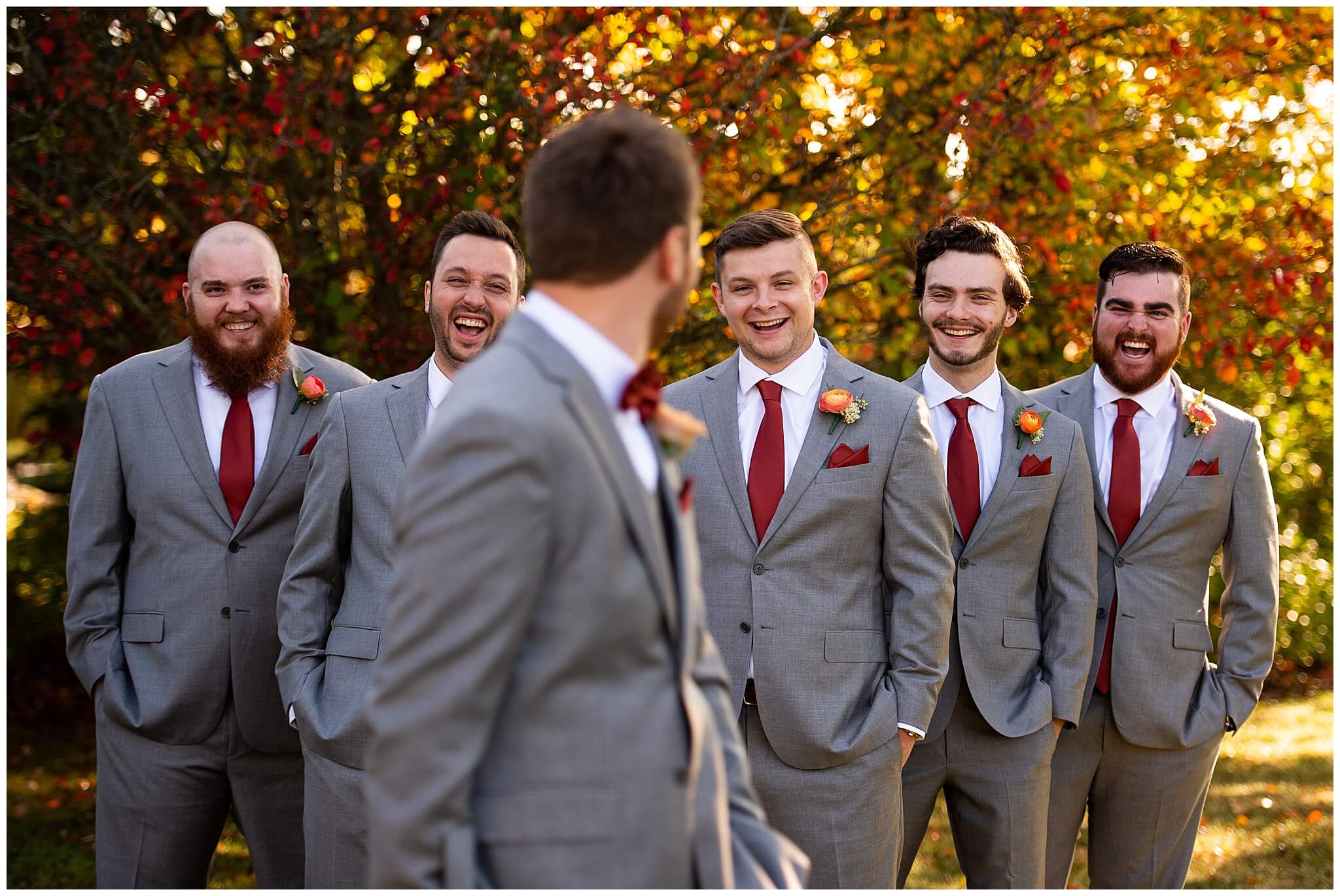 a groom is heckled by his groomsmen in grey suits. Everyone is laughing
