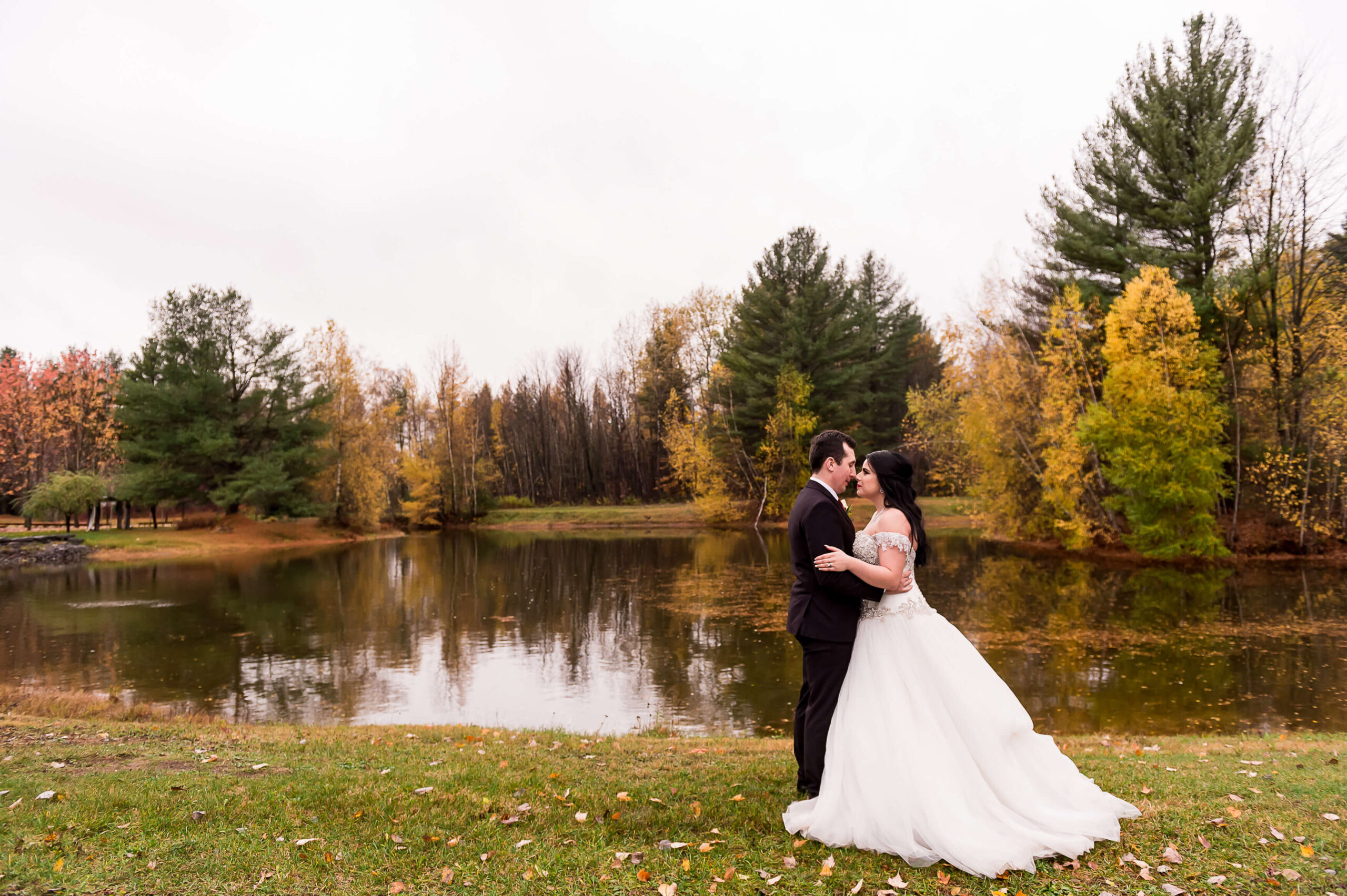 a bride and groom embracing surrounded by the fall colours of the pond at Bean Town Ranch weddings