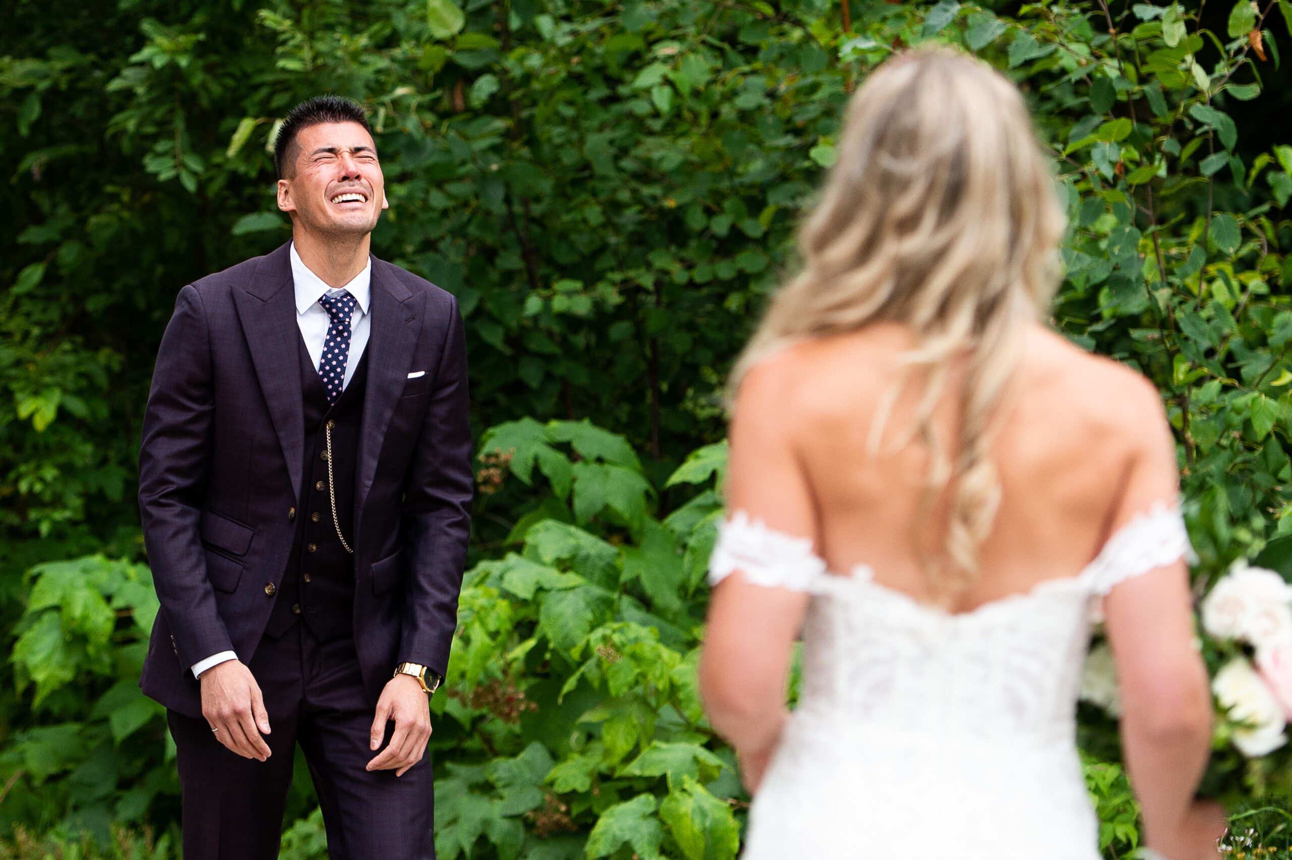 a groom in a 3 piece eggplant coloured suit cries emotionally as he sees his bride for the first time at Le Belvedere weddings. Captured outdoors by JEMMAN Photography
