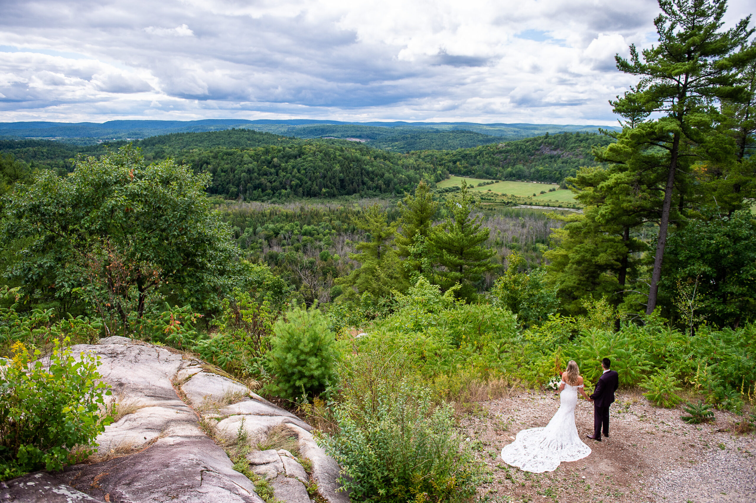 a bride and groom holding hands looking off into the distance of the Gatineau Hills at Le Belvedere weddings. Captured by JEMMAN Photography