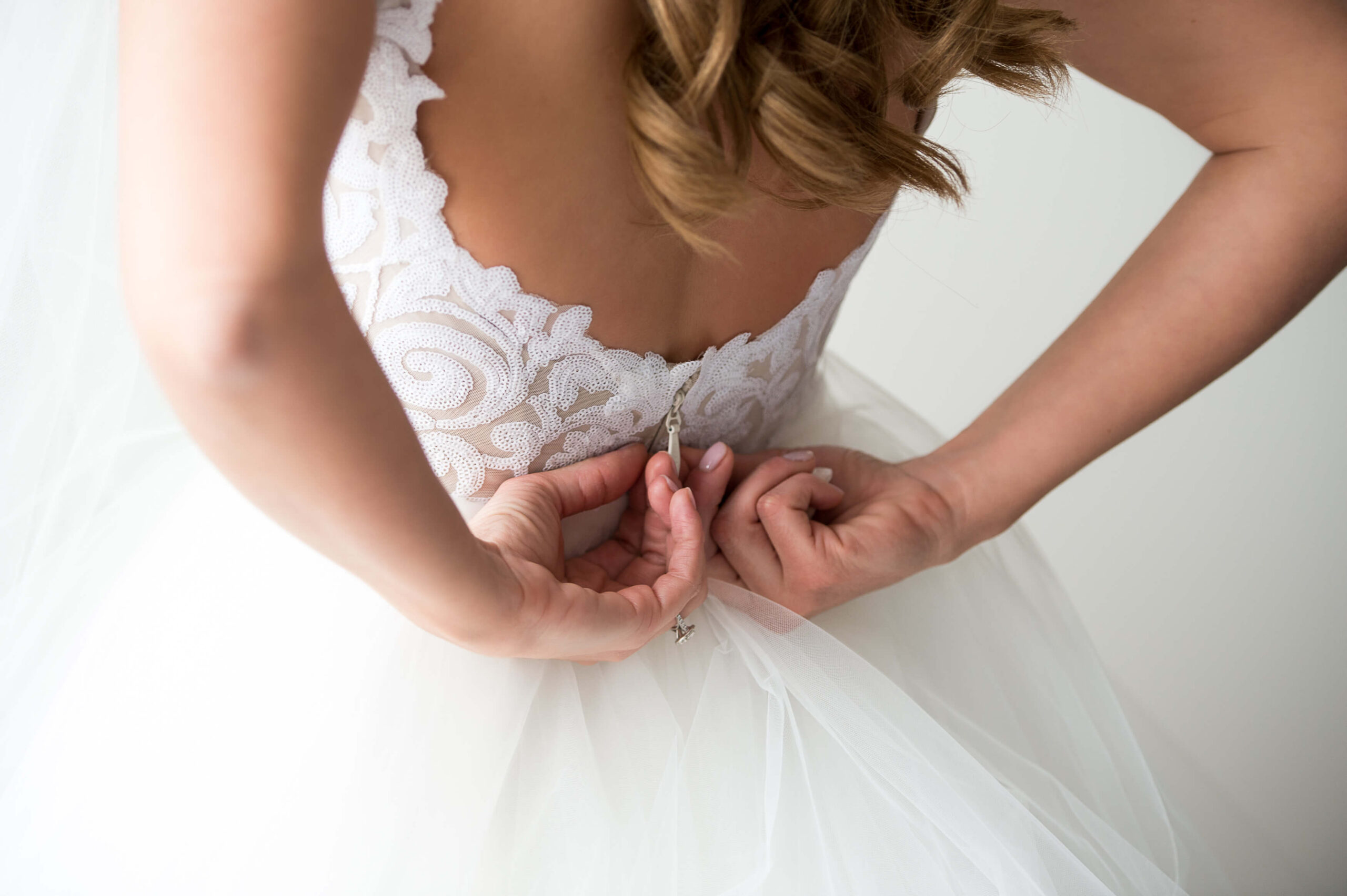 a photo of a bride zipping up the back of her dress taken as a part of her Ottawa bridal portraits