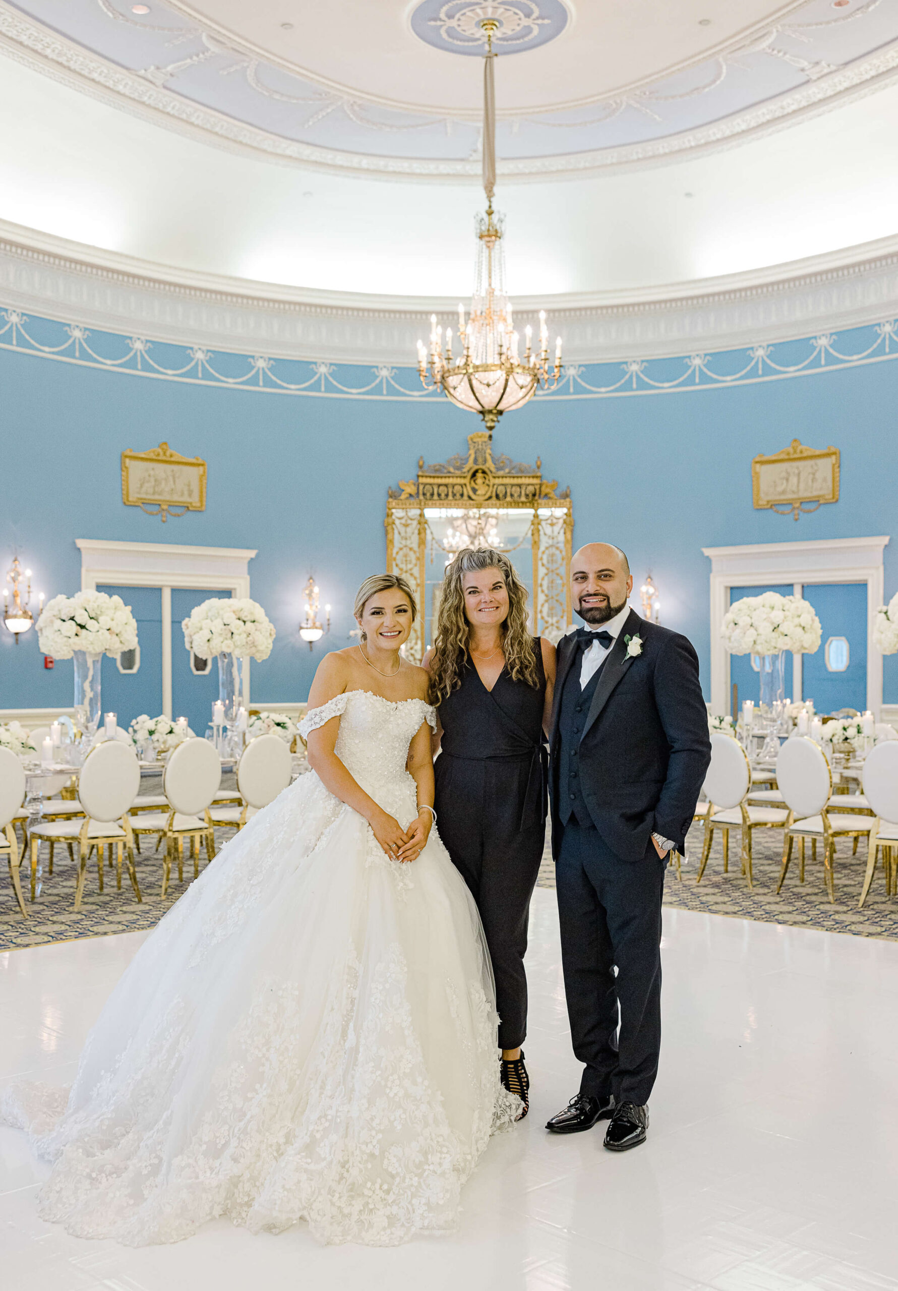 a photo of Erica Irwin Weddings & Events standing together with a bride and groom in the blue Adam Room of the Chateau Laurier