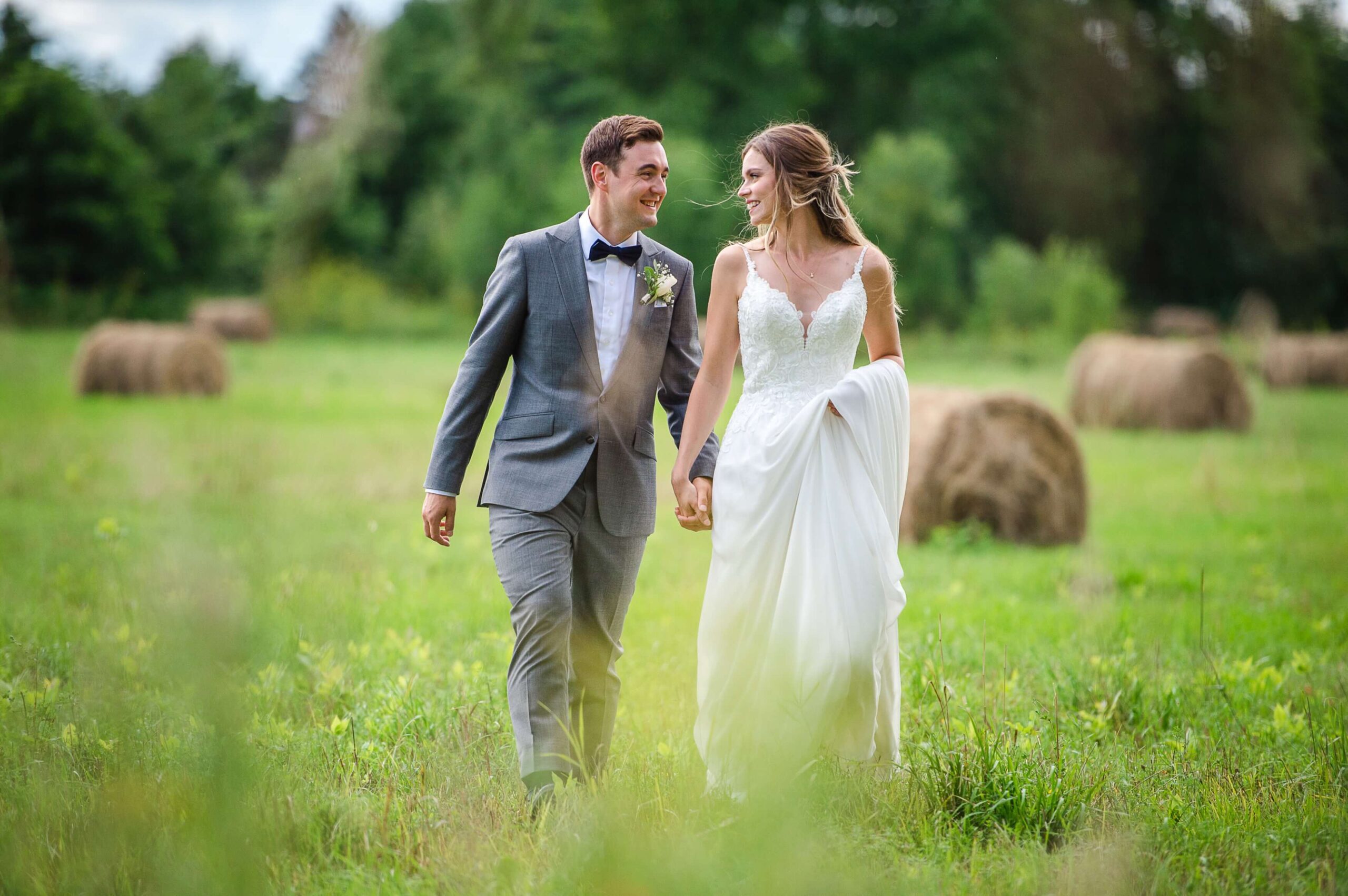 a bride and groom walking hand-in-hand among the hay bales at Jabulani Wedding Venue