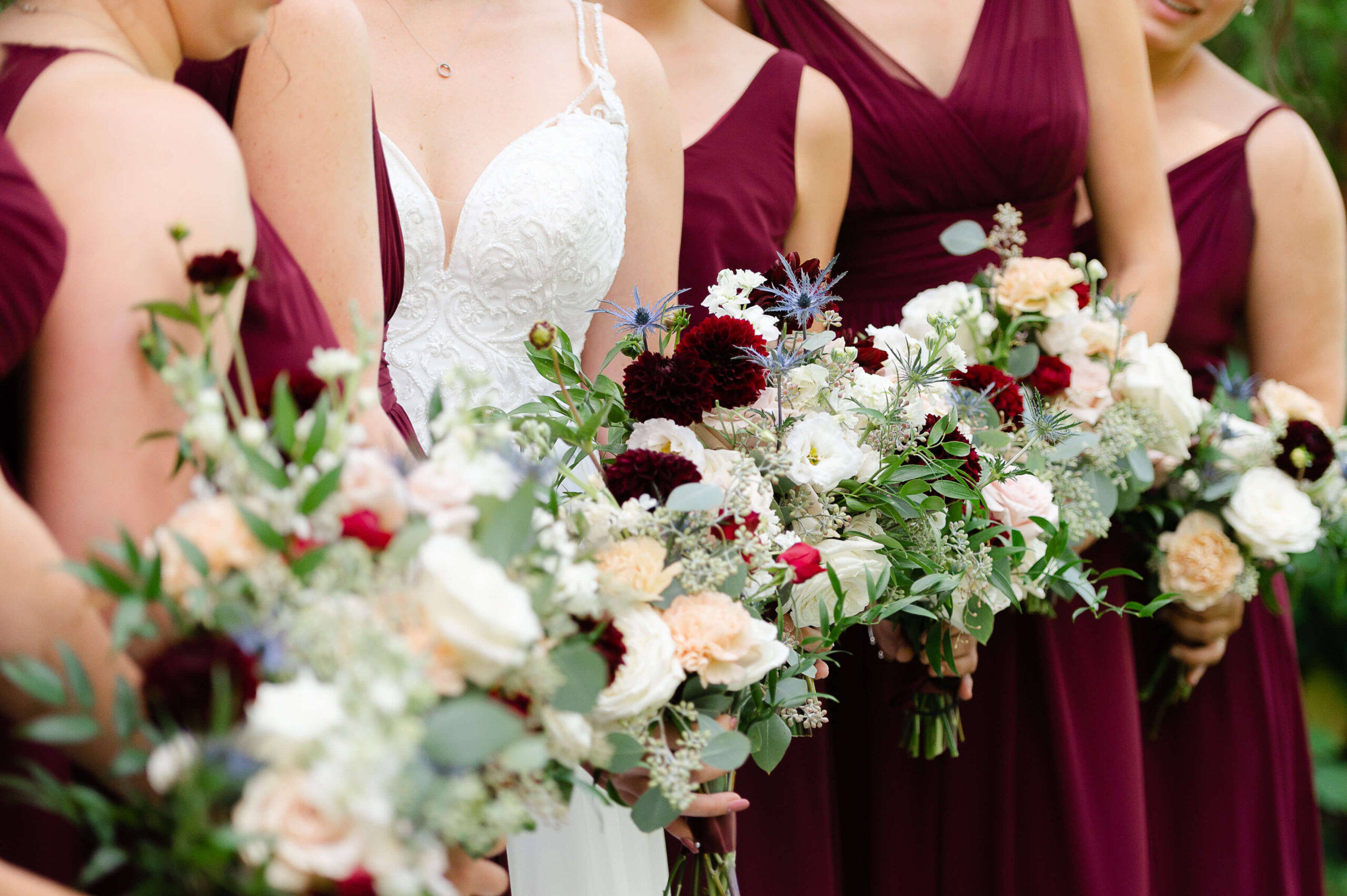 closeup photo of bridesmaid bouquets in burgundy all lined up in a row at a wedding organized by Opportunity Knocks Events