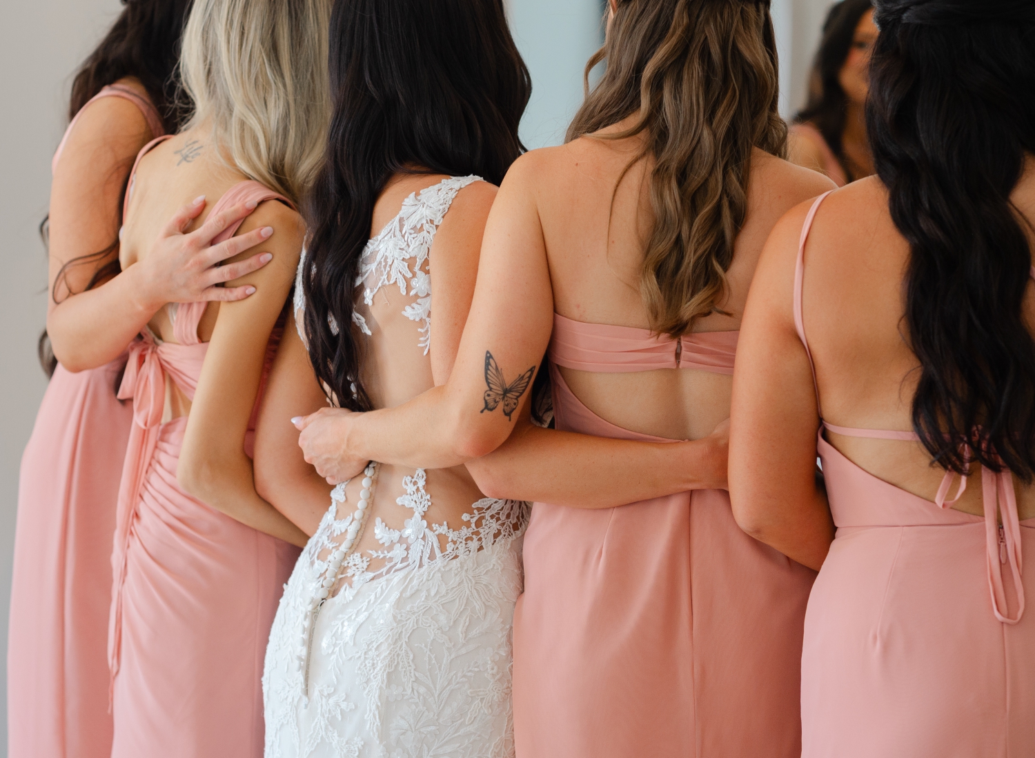 the back details of a bride's gown and her pink bridesmaids gown capture during her wedding at the Bleeks and Bergamot Wedding Venue