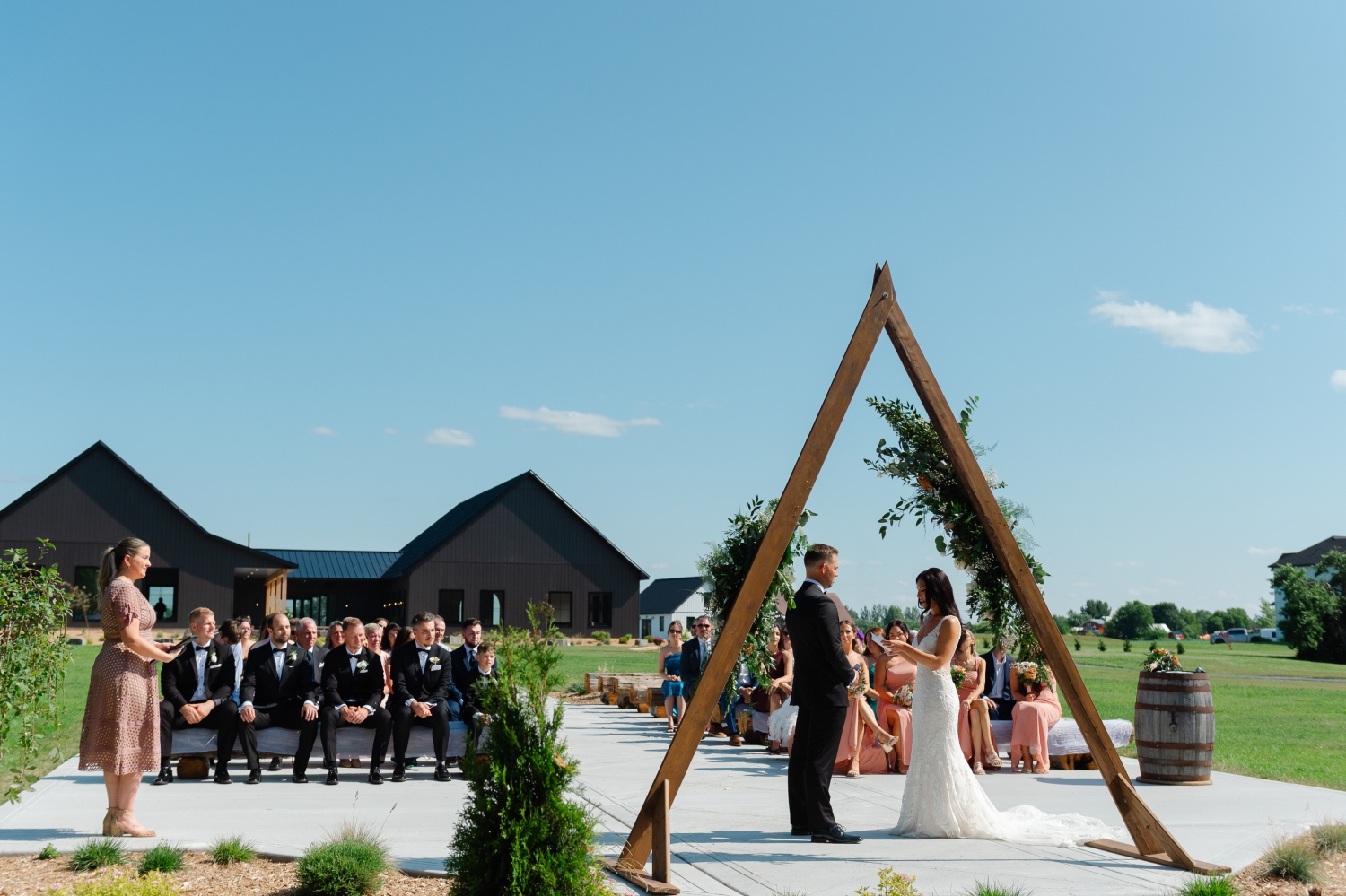 a wide angle photo showing a couple getting married with all of their guests and the Bleeks and Bergamot Wedding Venue in the background