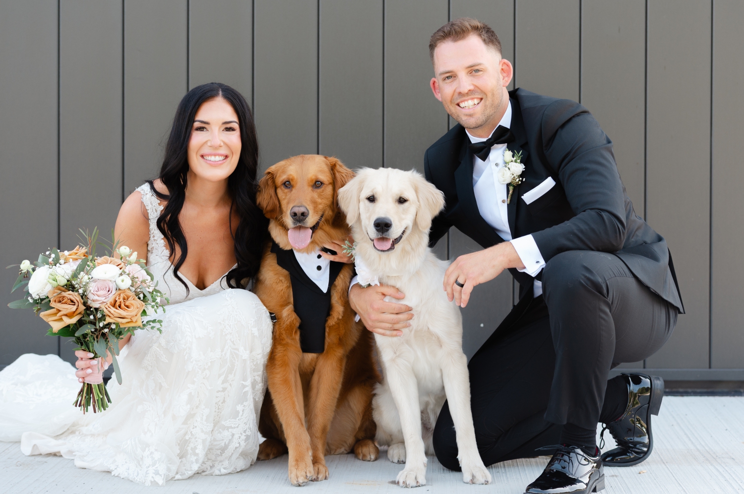 a bride and groom posing and smiling with their two golden retrievers during their Bleeks and Bergamot Wedding