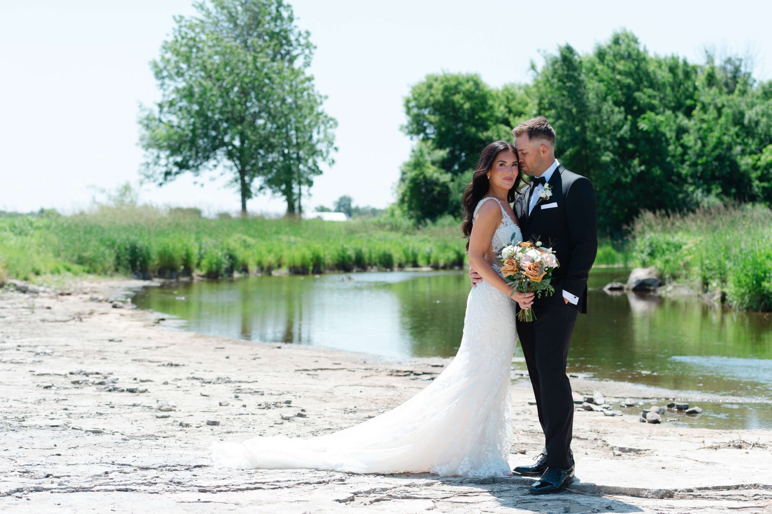 a bride and groom embracing on the riverside of the Bleeks and Bergamot Wedding Venue