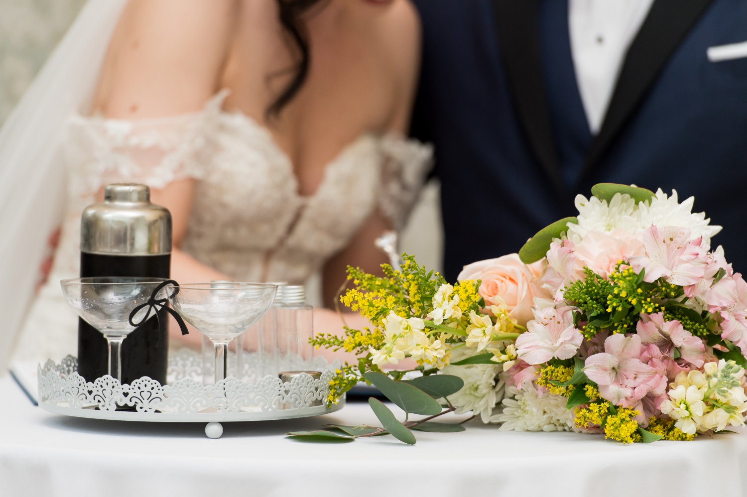 a closeup photo of a martini set and floral bouquet. Captured as the bride and groom sign their marriage certificate 
