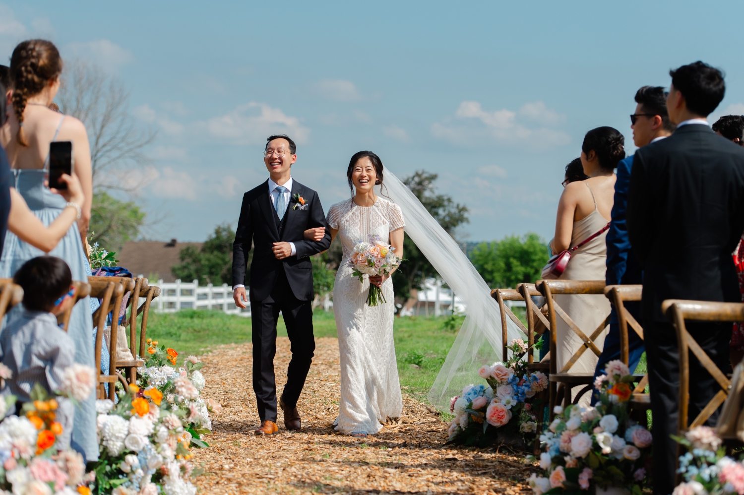 a smiling bride and groom walking themselves down the aisle as part of their Ottawa backyard wedding ceremony