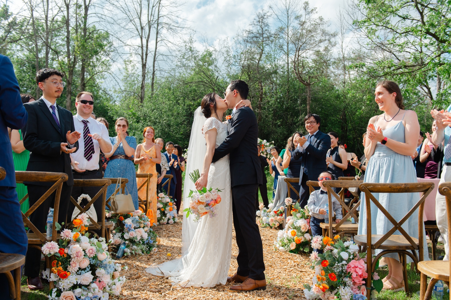 a bride and groom kiss in the centre of the aisle during their Ottawa backyard wedding recessional