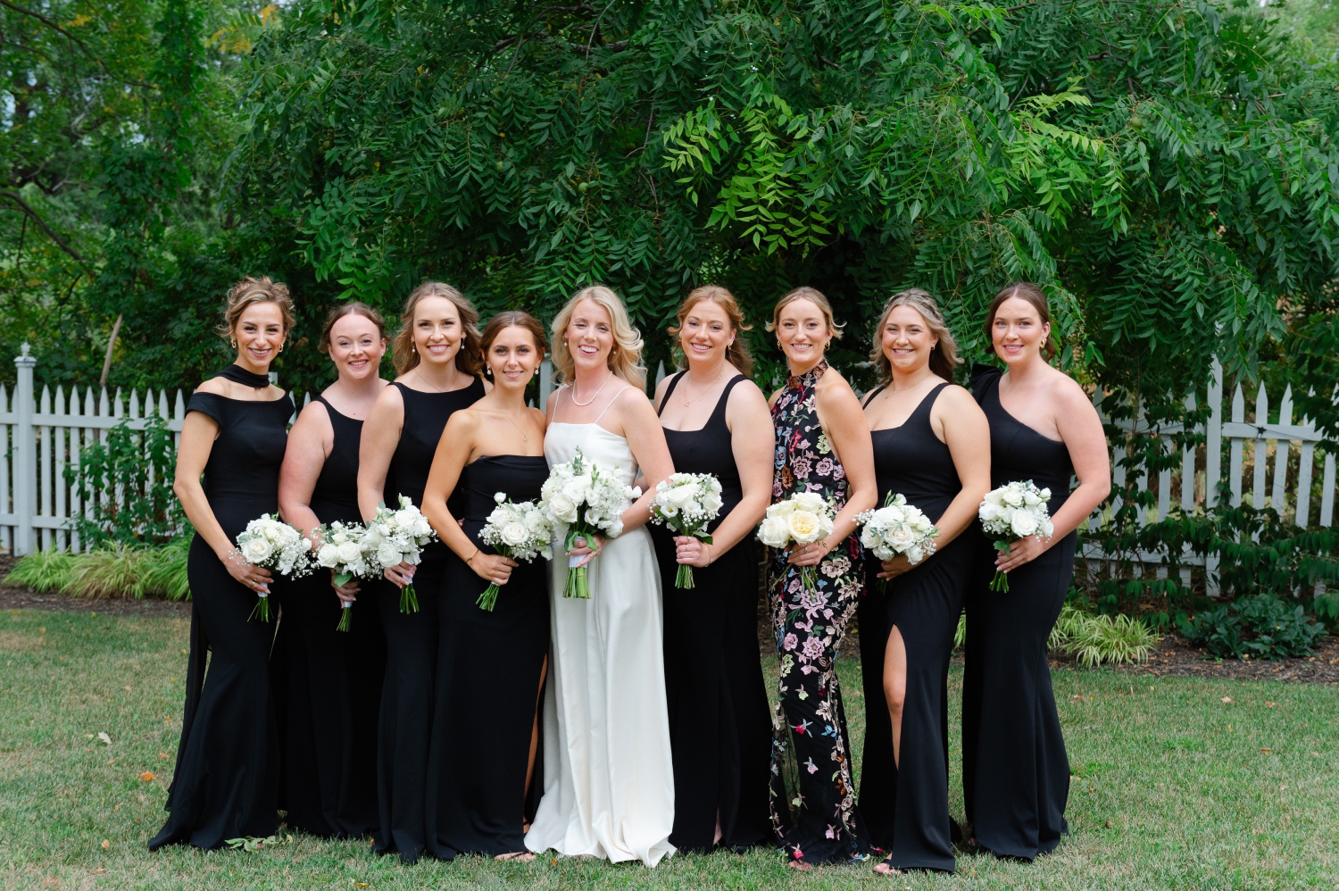 a formal portrait of a bride with her bridesmaids dressed in black gowns as they wait to leave for the bride's Ottawa tented wedding