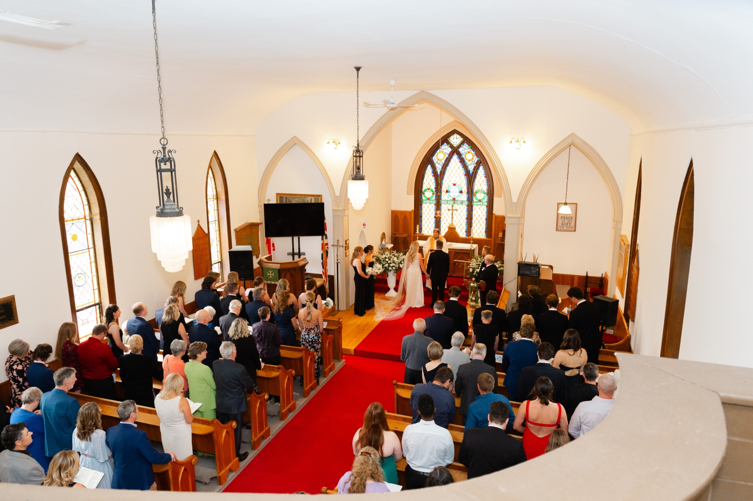 a photo of a church ceremony taken from the balcony showing the bride and groom and all their guests. Captured by Ottawa wedding photographer JEMMAN Photography