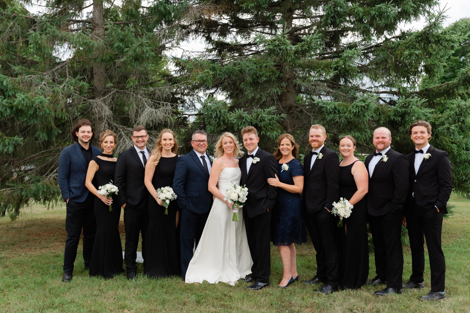 a family photo showing a bride and groom with their parents and siblings. Captured outdoors by Ottawa wedding photographer JEMMAN Photography