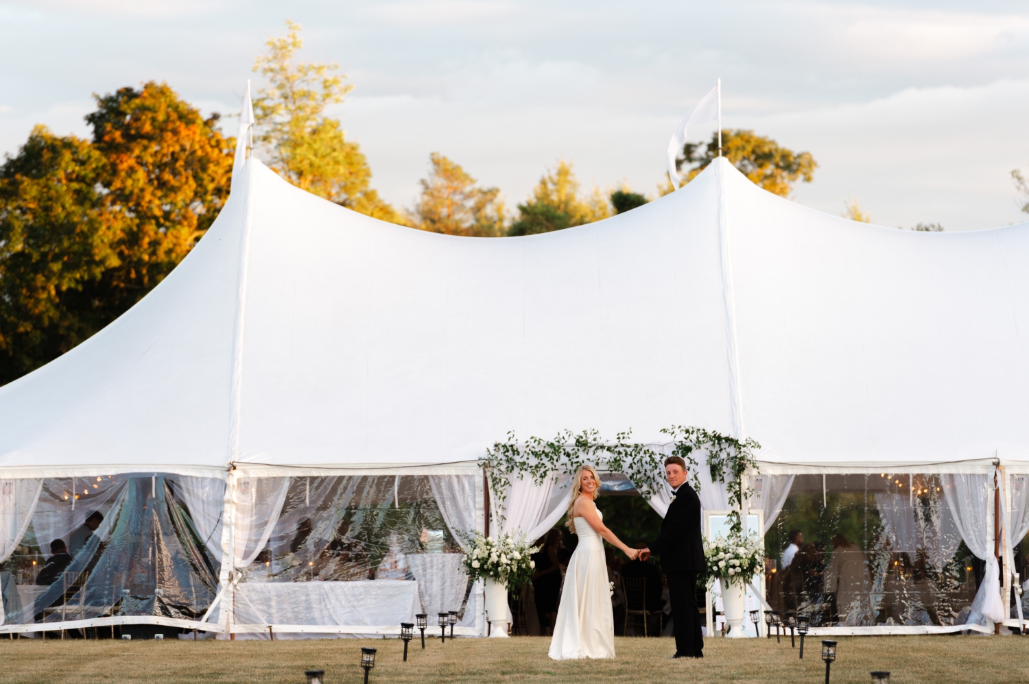 a bride and groom standing outside their Ottawa tented wedding reception holding hands and ready to go in to greet their guests