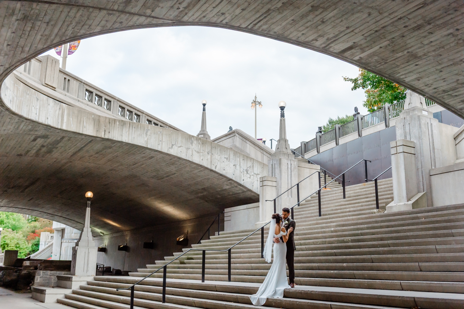 a wide angle capture of a bride and groom embracing and smiling on the steps of the NCC underpass before they leave for their Restaurant 18 Wedding