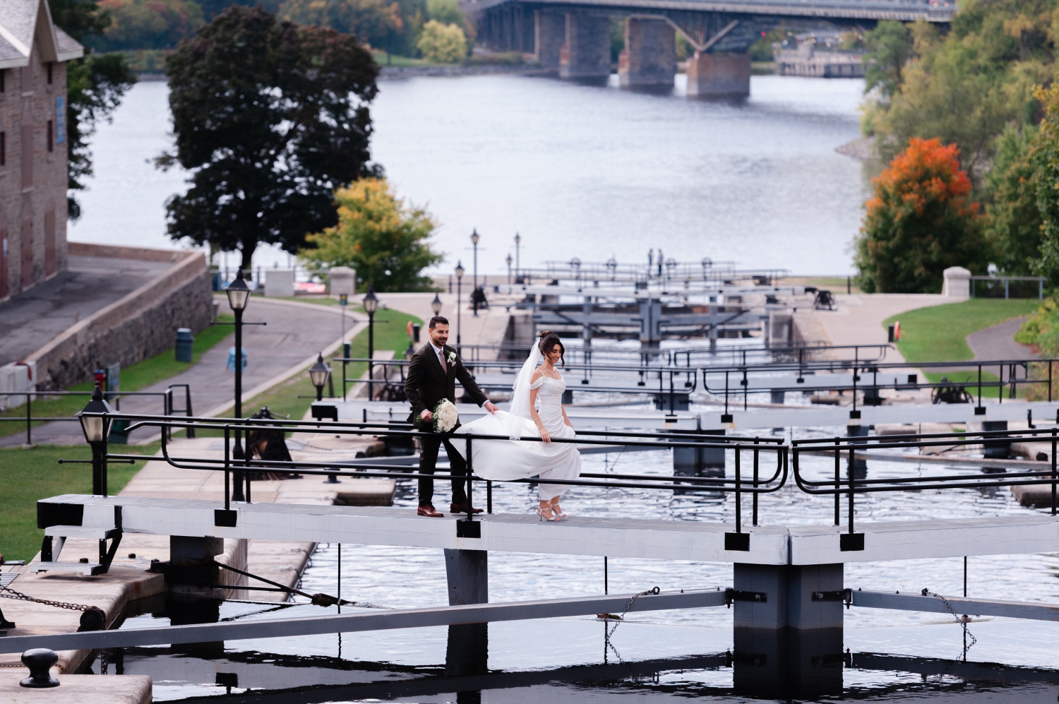 a bride and groom walking carefully across the downtown locks. Captured by Restaurant 18 Weddings photographer JEMMAN Photography