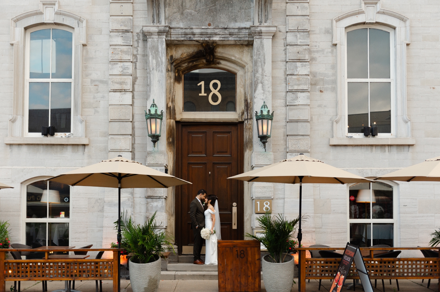 a bride and groom kissing under the 18 sign before they enter their Restaurant 18 Wedding reception