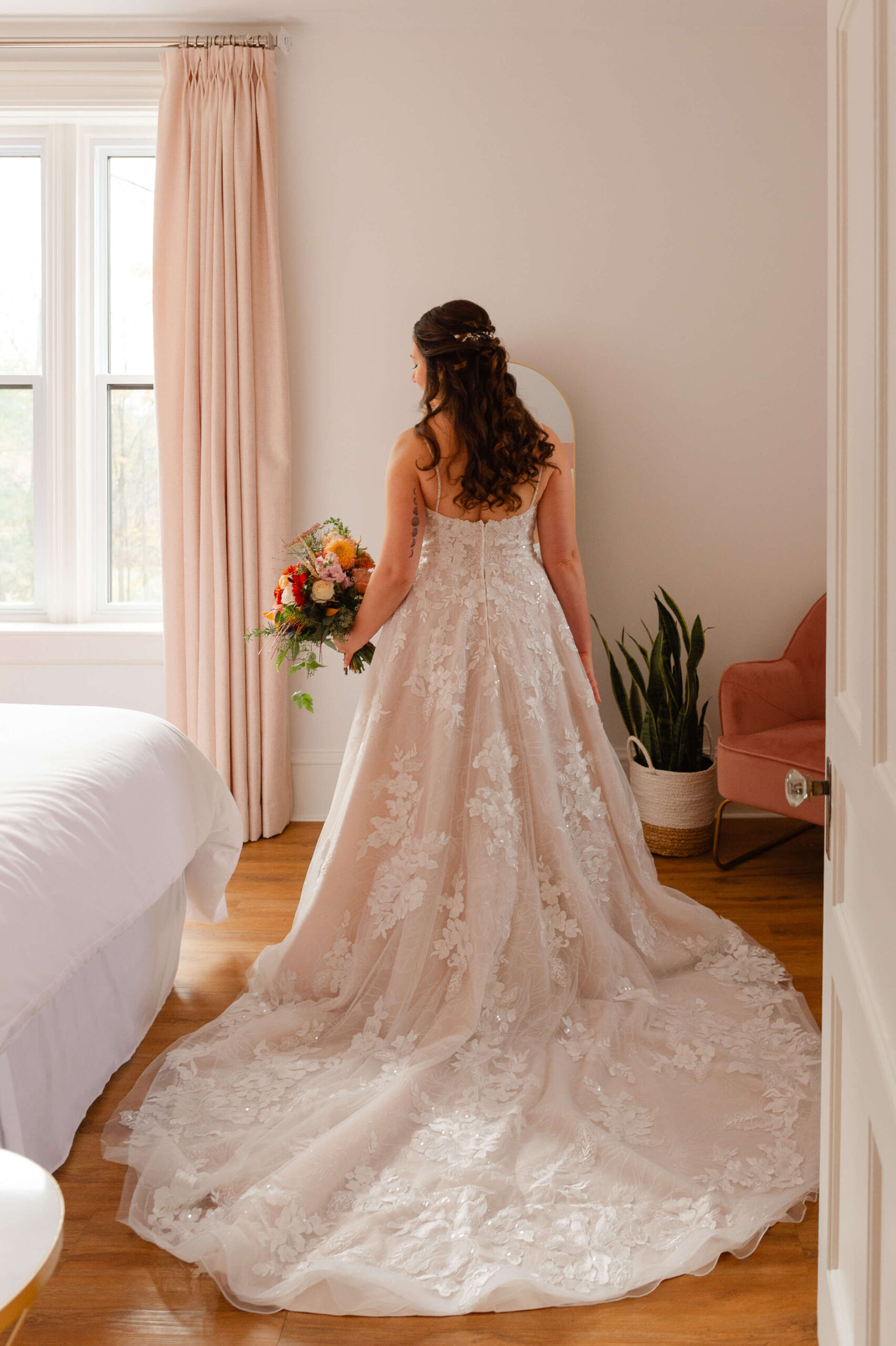 a full length photo of a bride showing the back details and train of her dress. Captured in the Rose Room at Maple and Rose Weddings by JEMMAN Photography