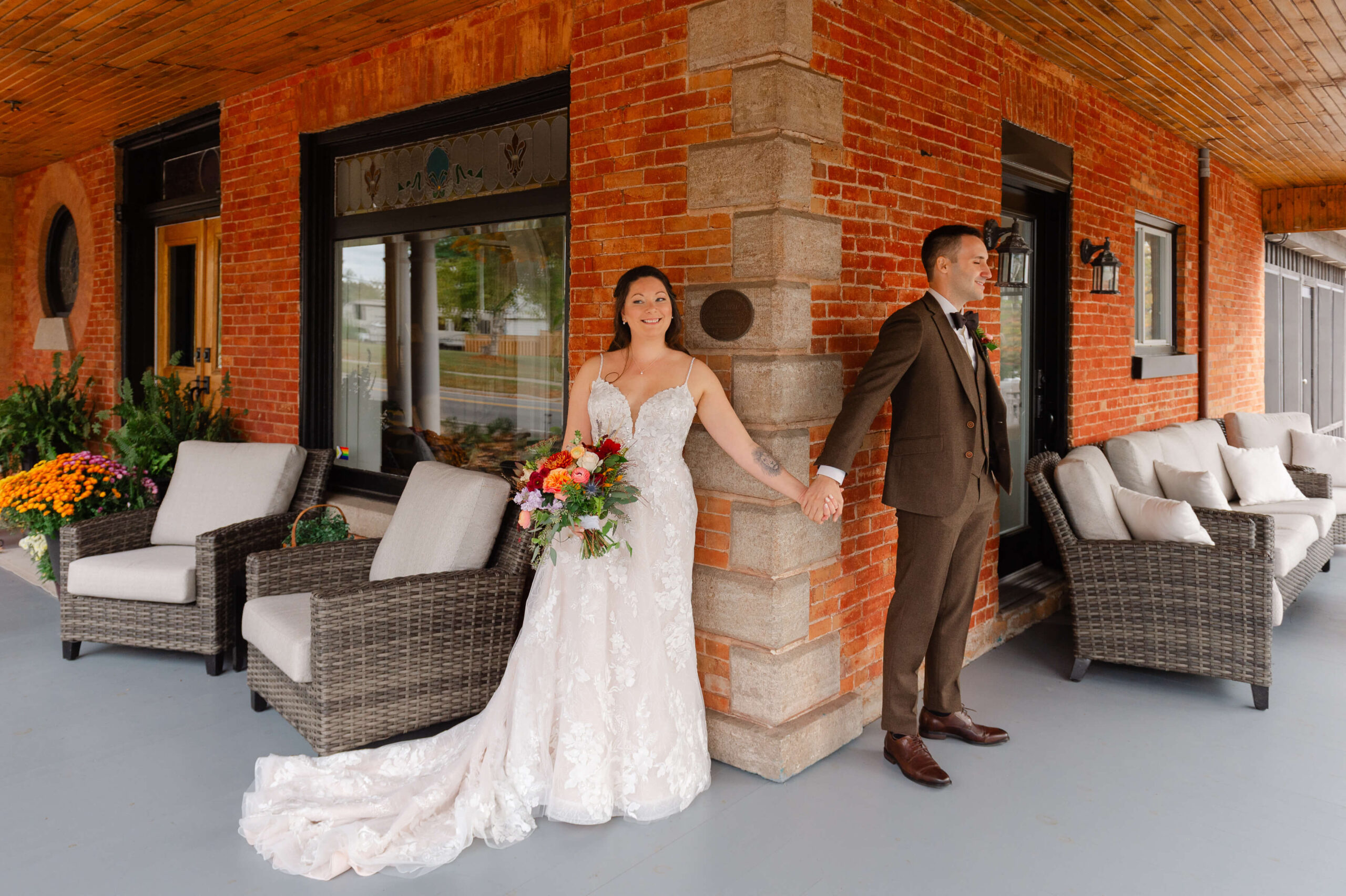 a bride and groom holding hands around the corner of the veranda at Maple and Rose wedding venue and accommodations just about to see each other for the first time. Captured by JEMMAN Photography
