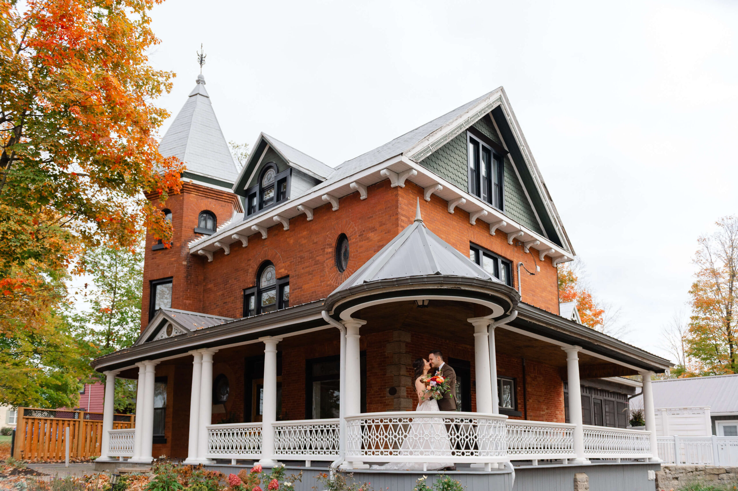 a bride and groom kissing on the front porch of Maple and Rose wedding venue and luxury accommodations. Captured by JEMMAN Photography