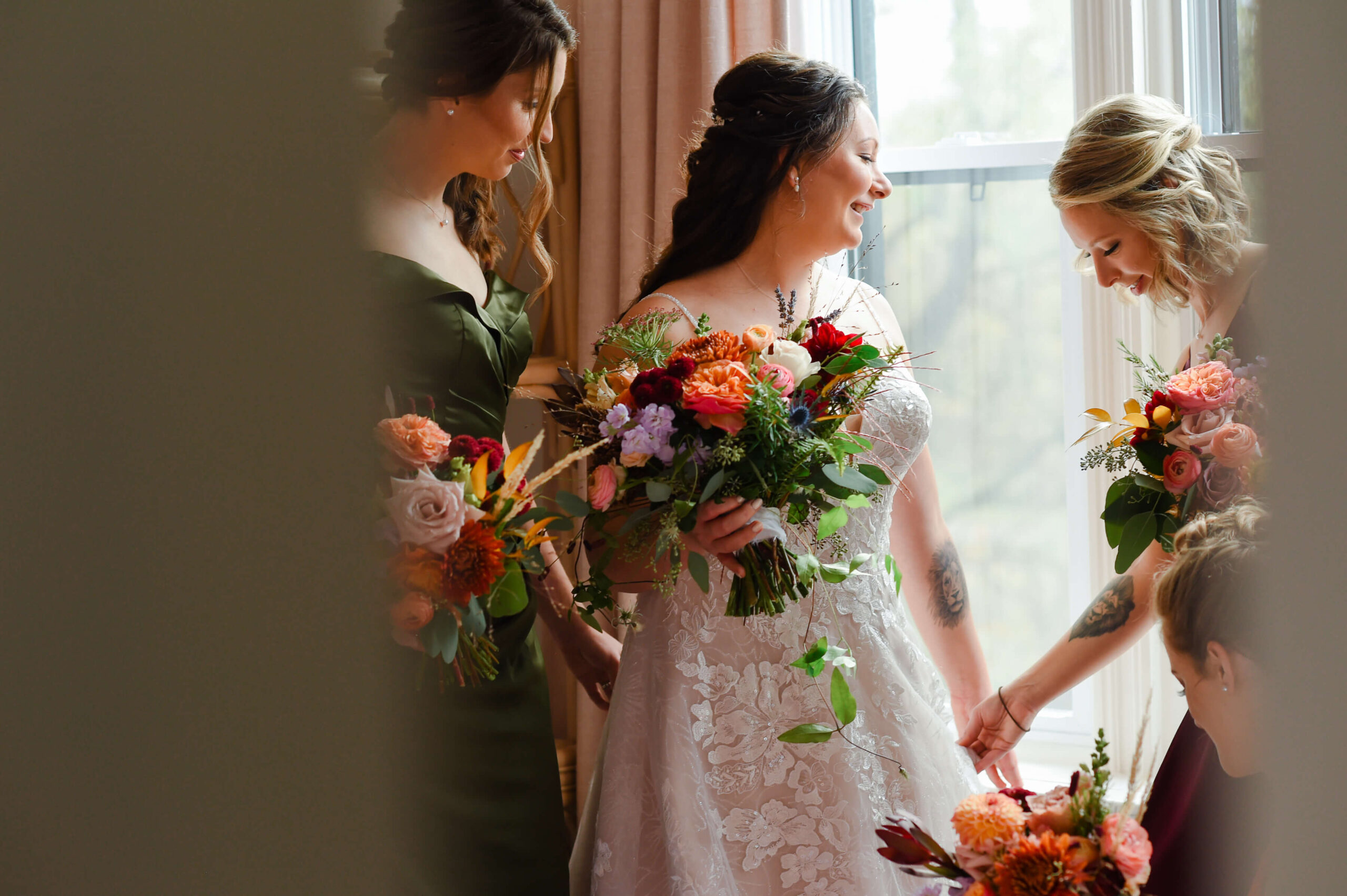a bride and her bridesmaids holding their fall coloured bouquets and getting ready for her Maple and Rose wedding. Captured indoors in the The Rose Room by JEMMAN Photography