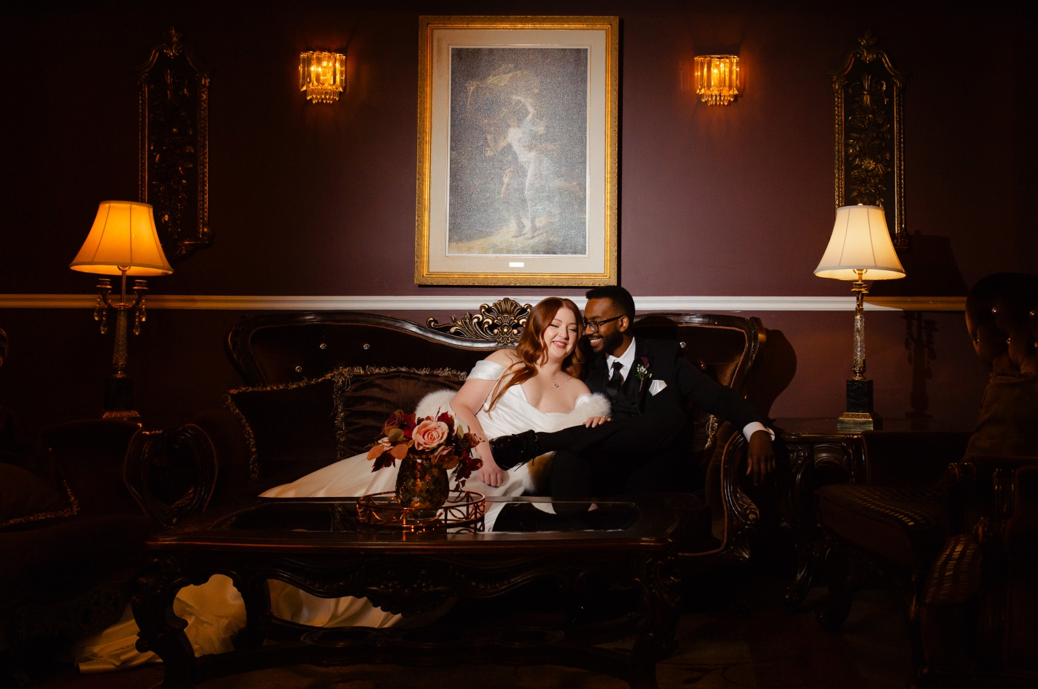 a spotlit photo of a bride and groom sitting on the couch in the Ballroom of the Grand Hotel Weddings. Captured by JEMMAN Photography
