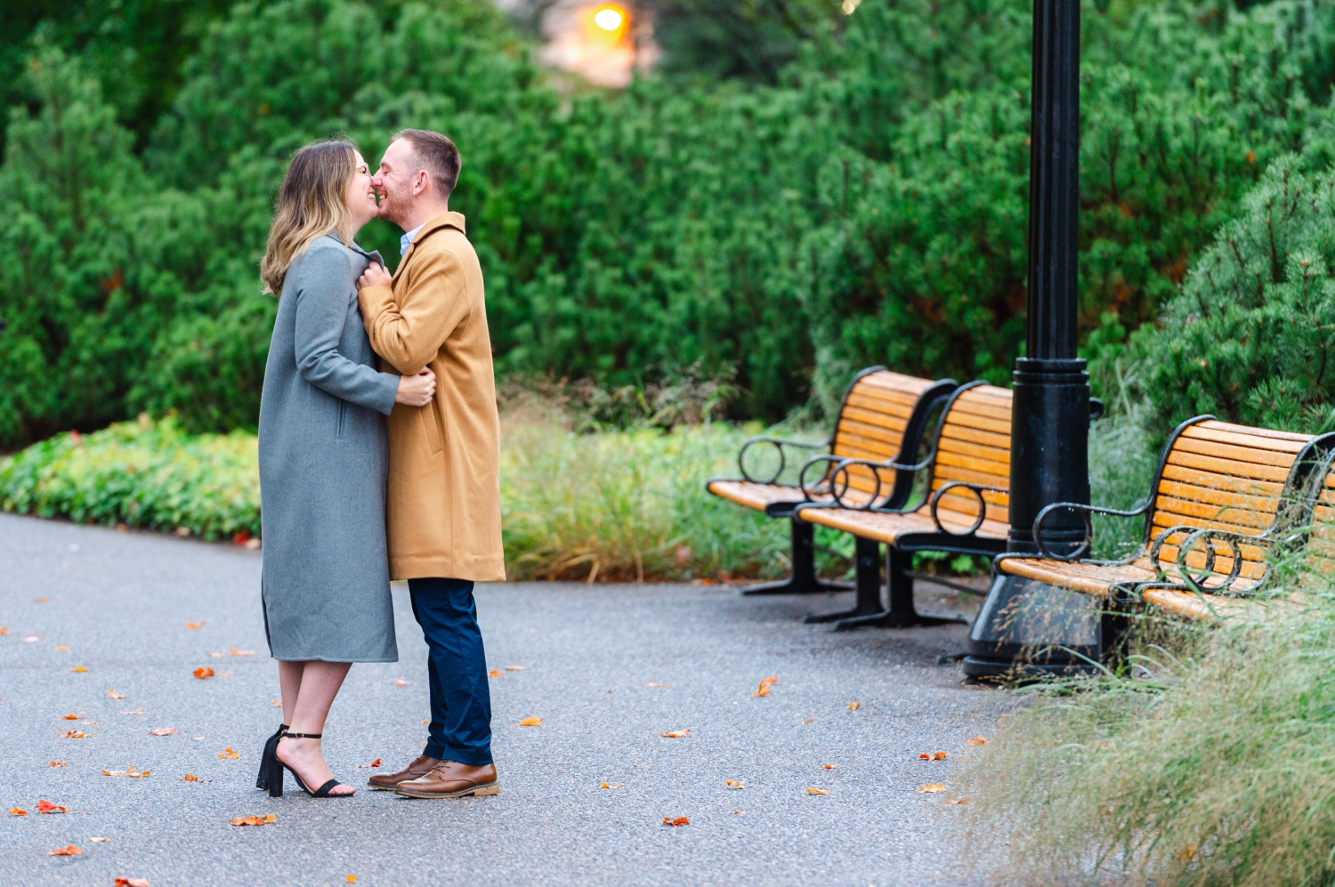 a male in a camel coloured jacket kissing a female in a grey jacket as part of their Ottawa engagement session. Captured by JEMMAN Photography