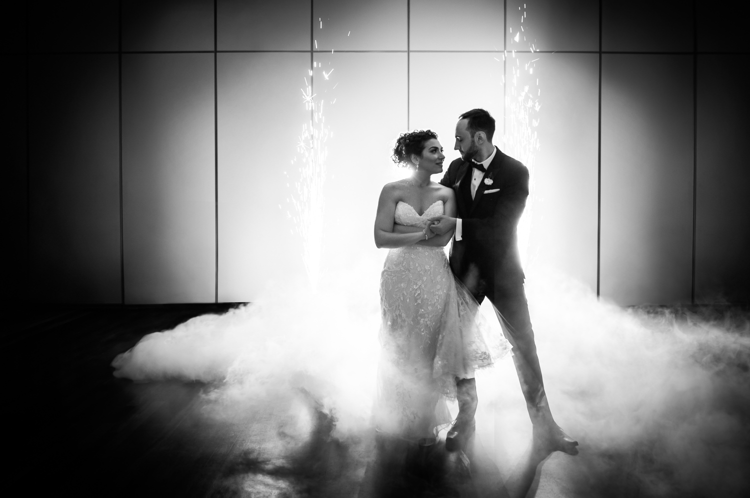 a black and white photo of a bride and groom with smoke billowing around them as they dance their first dance they learned with wedding dance lessons in Ottawa