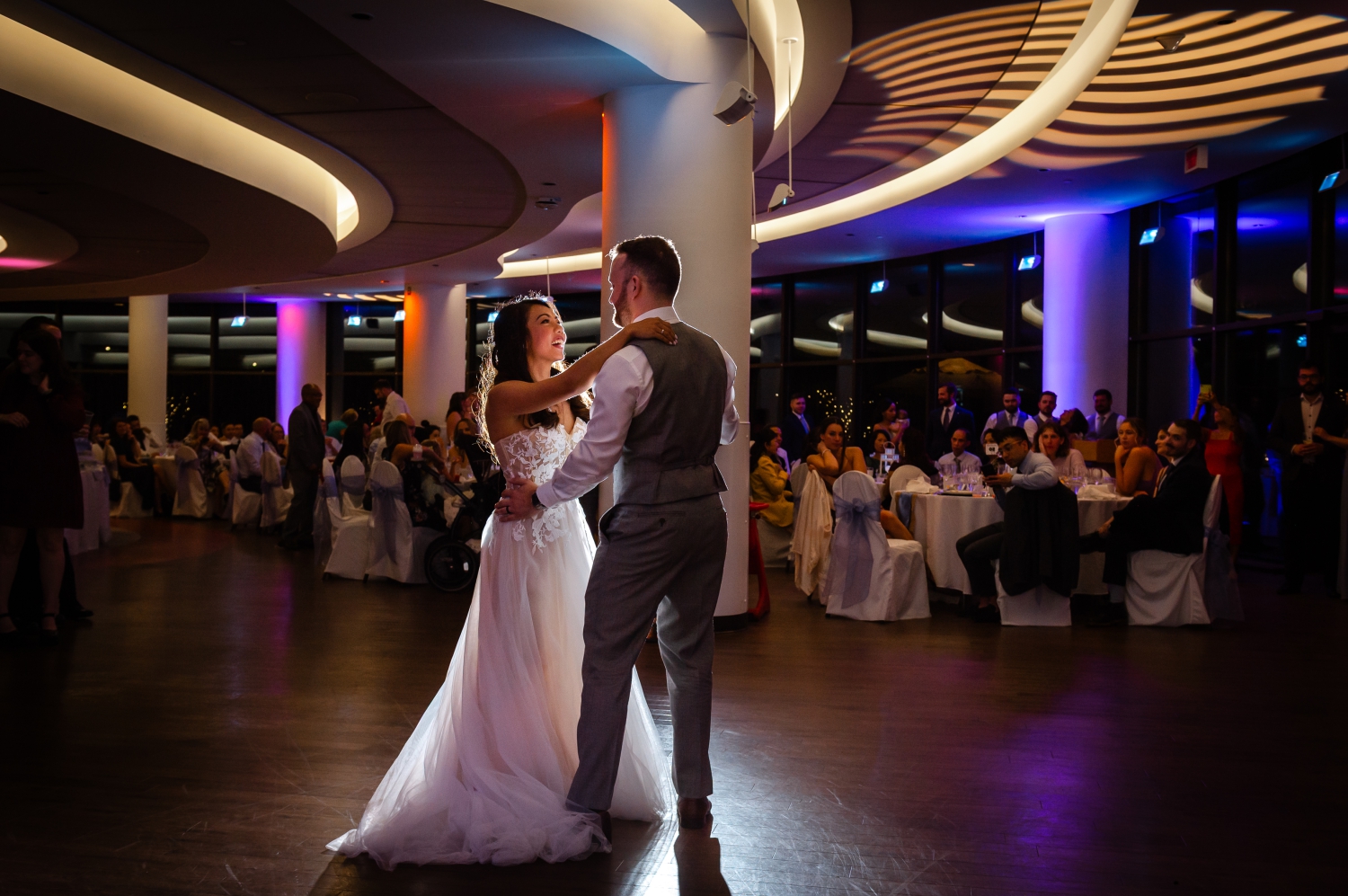 a bride and groom smiling at each other as they dance their first dance that they learned with wedding dance lessons in Ottawa