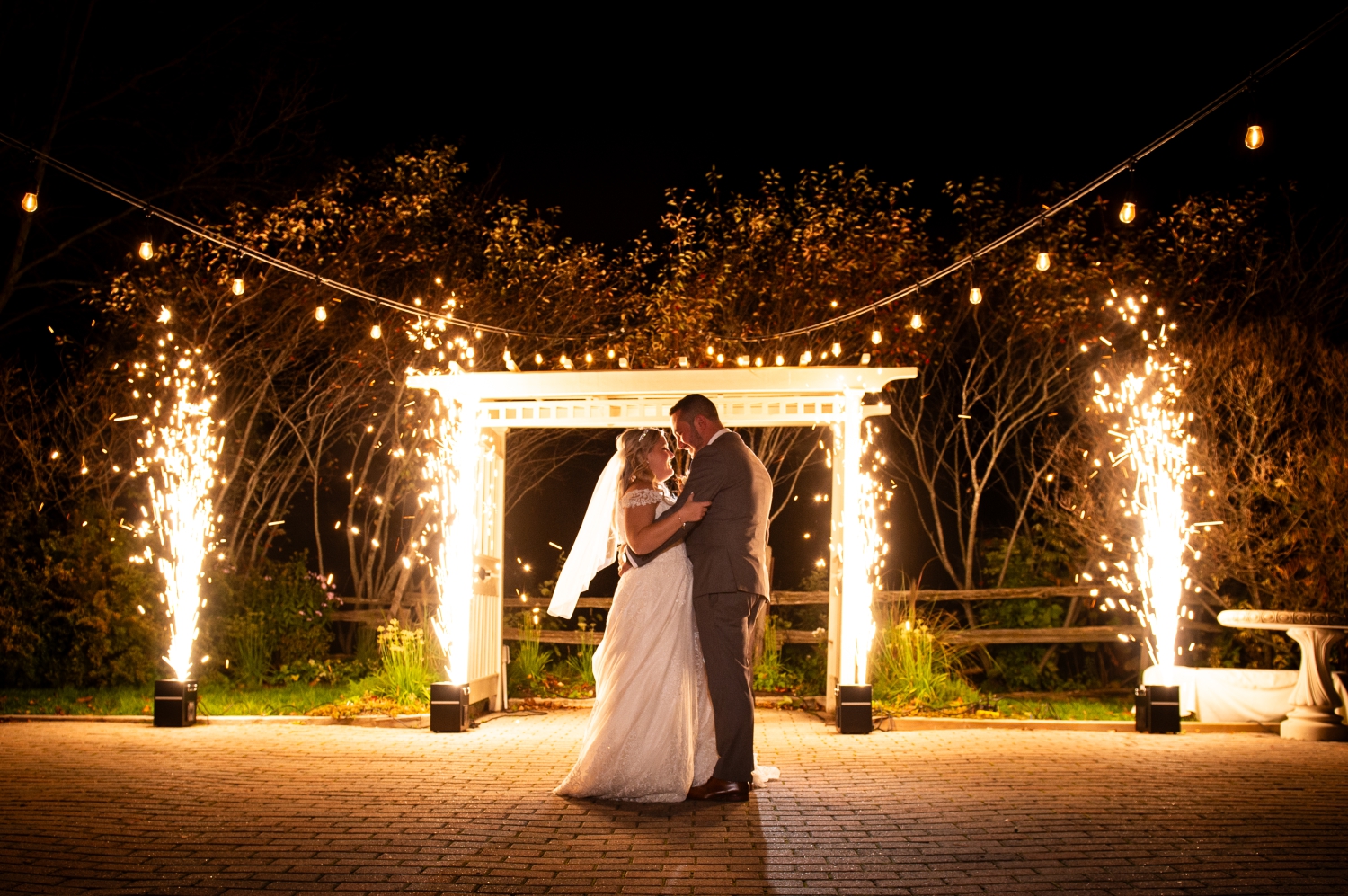 a bride and groom dancing the steps of their first dance that they learned at wedding dance lessons with cold sparklers going off behind them