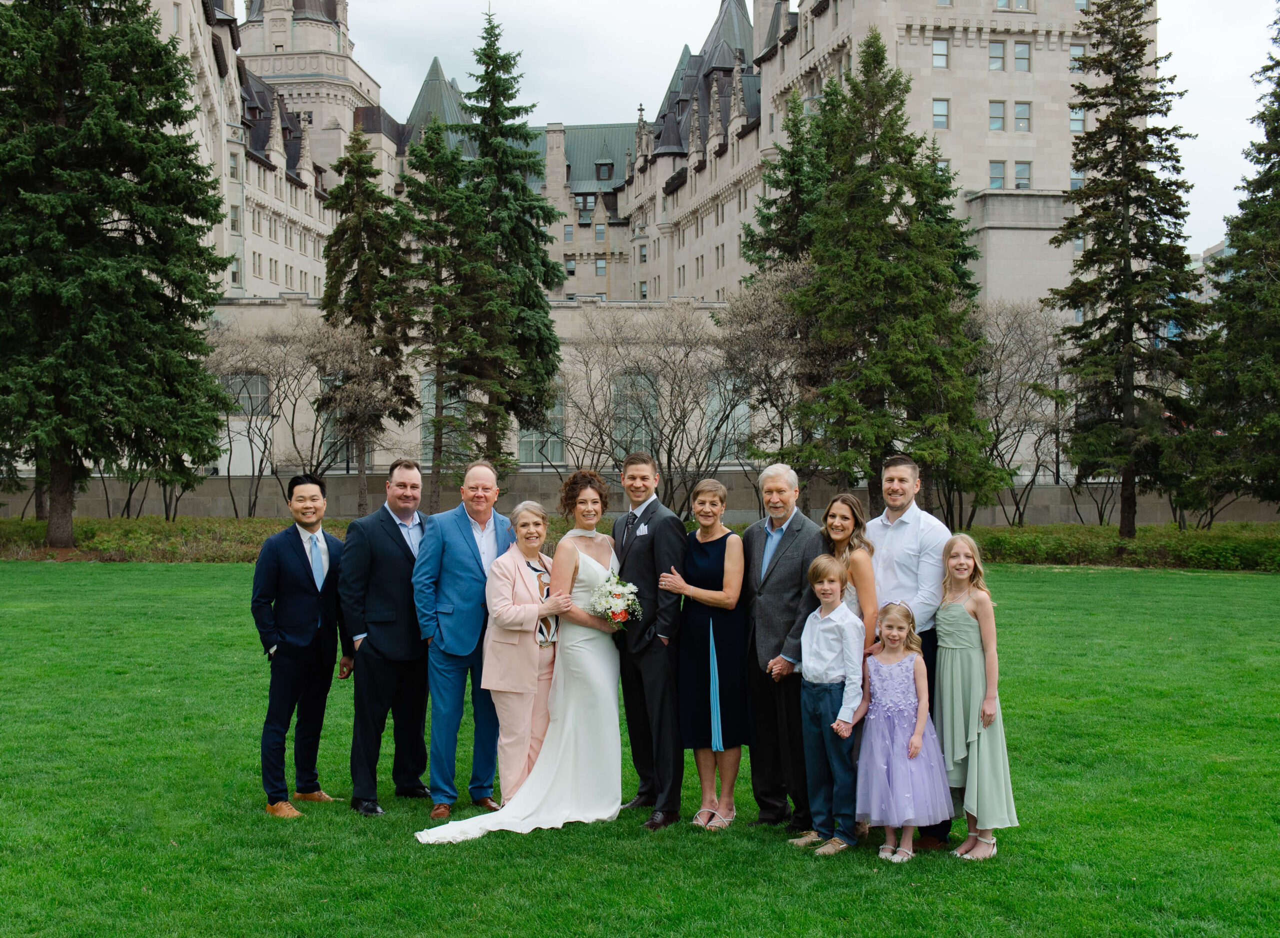 a family photo of 13 people with the Chateau Laurier in the background. Captured by JEMMAN Photography