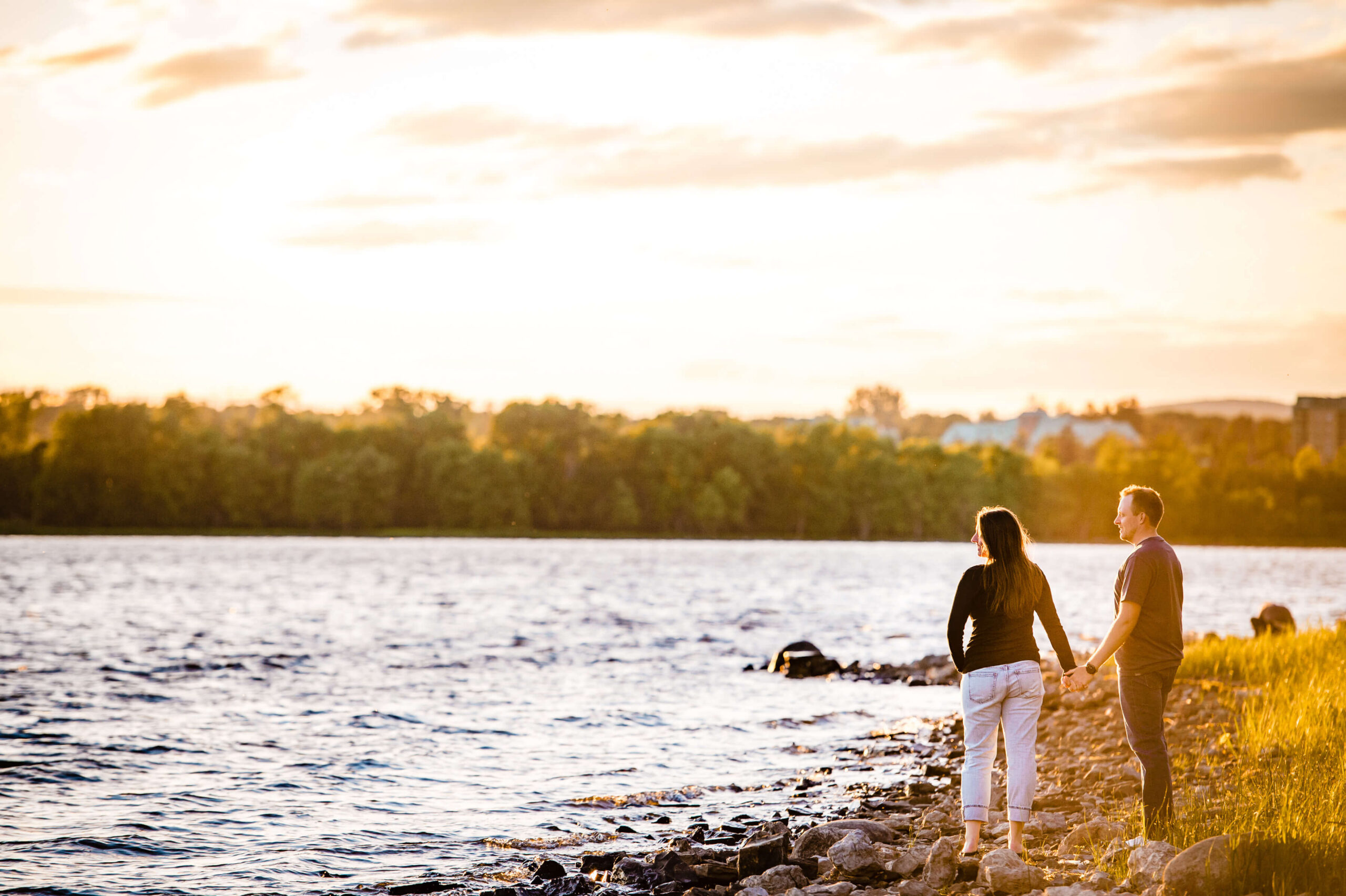 a male and female in black t-shirts and jeans holding hands at sunset at Dow's Lake, one of the best places to propose in Ottawa.